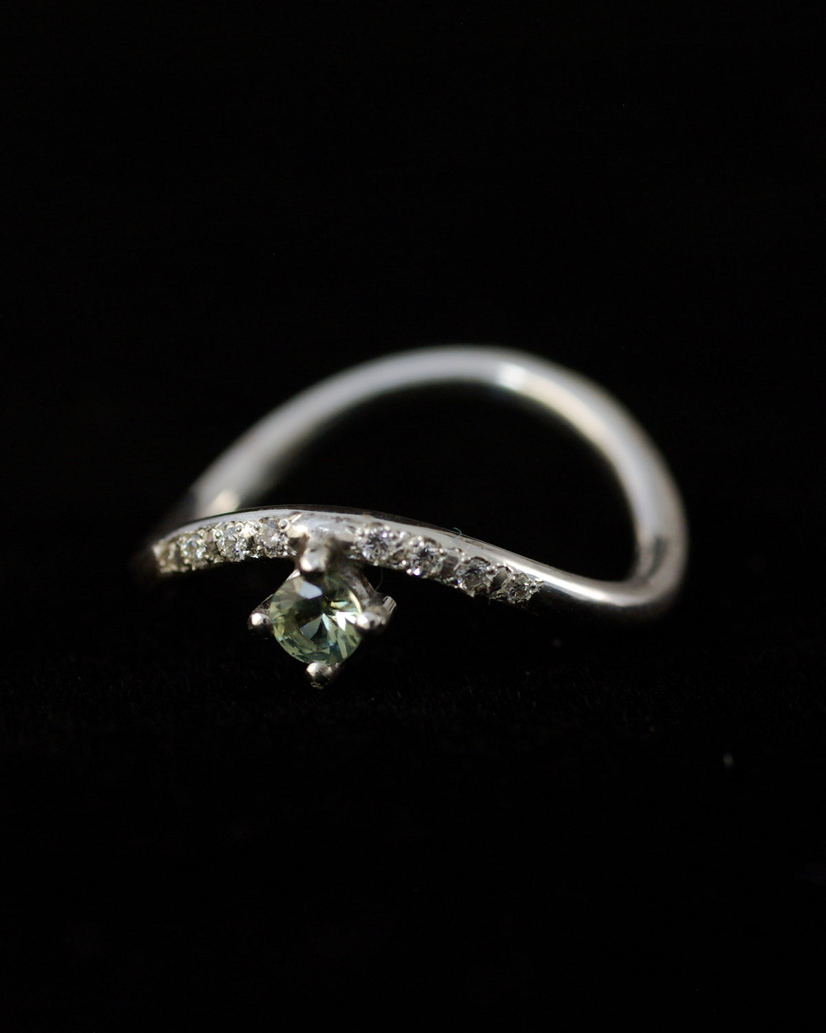 Vue à l'envers d'une bague en argent 925 ondulée avec pierre verte et petits diamants