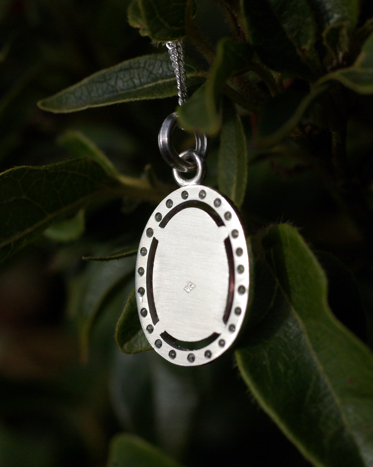 Dos d’un pendentif en argent avec fond non ajouré réfléchissant la lumière sous une tourmaline bicolore