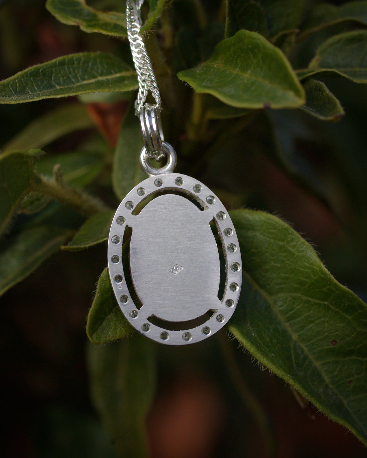 Dos d’un pendentif en argent avec poincçon d'artisan en losangesous une tourmaline bicolore