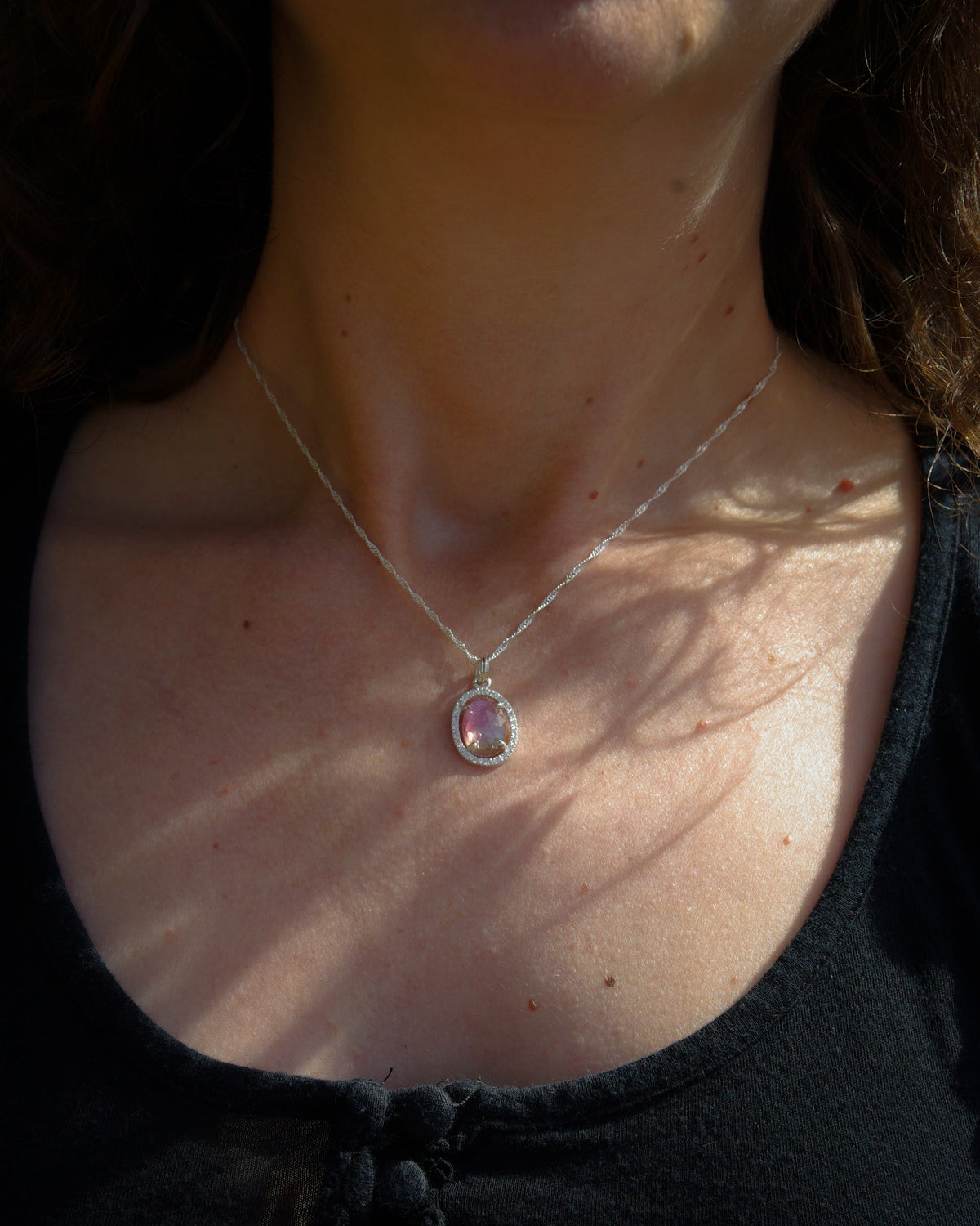 Vue porté d'un pendentif avec tourmaline rose bicolore ovale, aux nuances passant du rose à la transparence