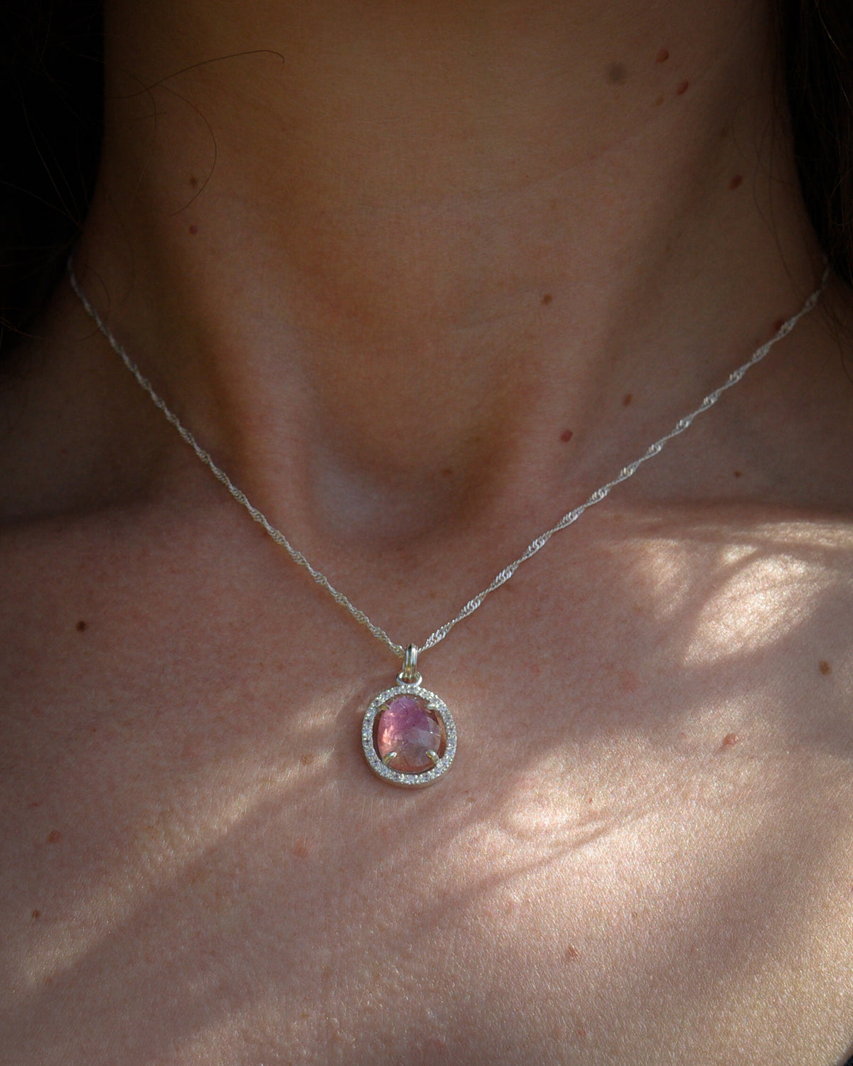 Vue porté d'un pendentif avec tourmaline rose bicolore et entourage oxydes de zirconiums