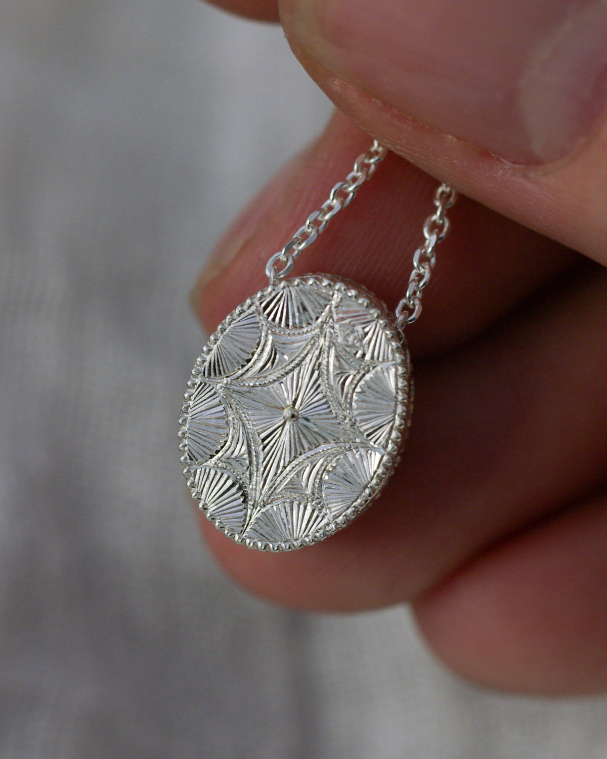 Dos d’un pendentif en argent entièrement gravé à la main avec chaînette traversant le bijou
